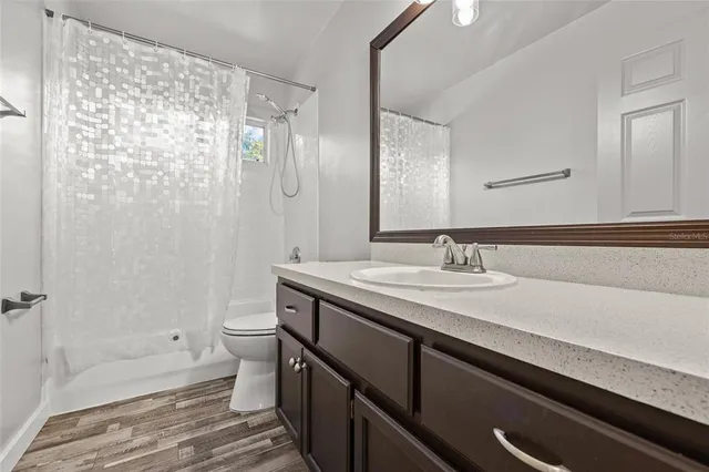 a bathroom with a granite countertop sink a toilet and shower