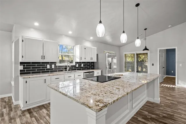 a large kitchen with granite countertop a sink a counter space appliances and cabinets