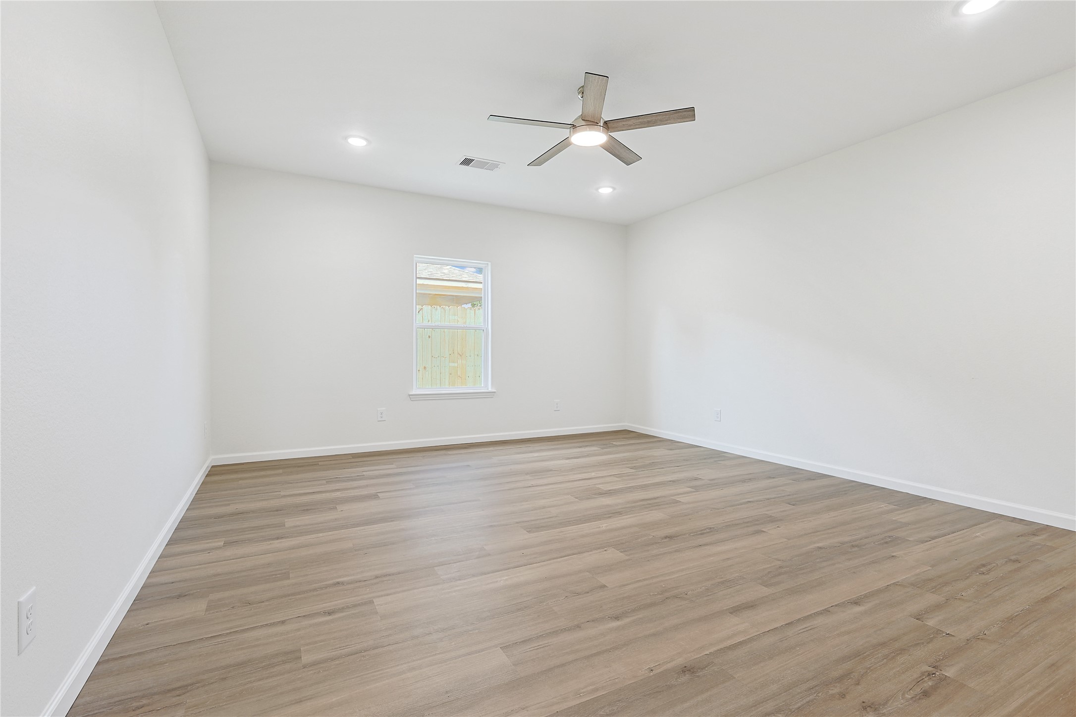 2317 Cedar Street Pearland, TX 77581 - Photo 18 of 33 an empty room with wooden floor fan and windows
