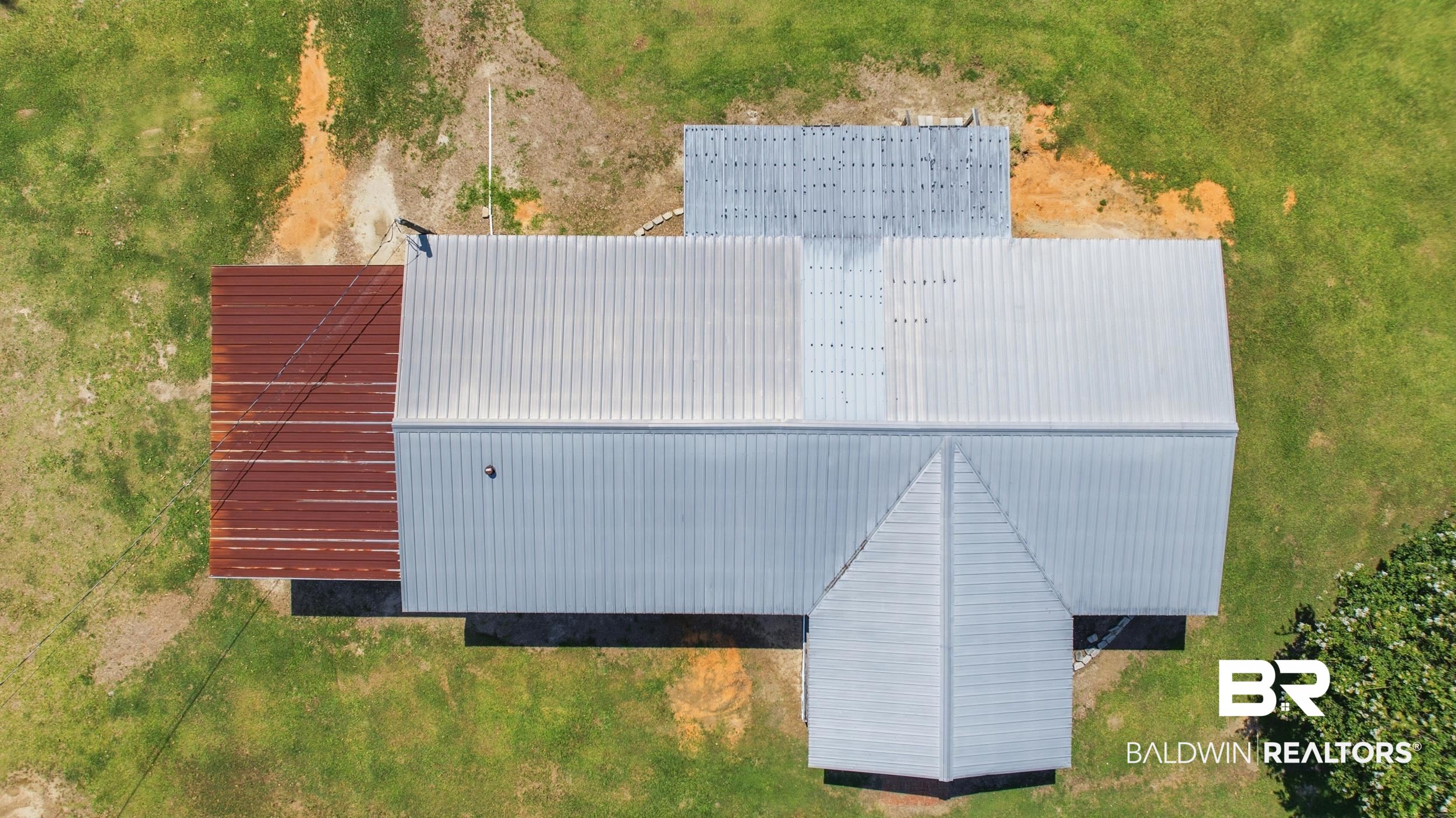 926 Tumbling Lane Atmore, AL 36502 - Photo 47 of 56 Building with multiple corrugated metal roof sections and surrounding green lawn