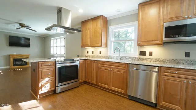 a kitchen with stainless steel appliances granite countertop a sink a stove a microwave and wooden cabinets