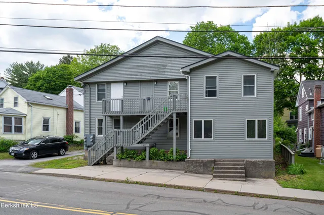 a front view of a house with a yard and potted plants