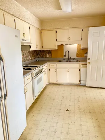 a kitchen with stainless steel appliances granite countertop a refrigerator sink and white cabinets