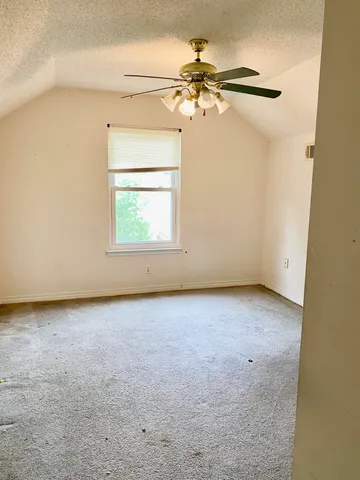 an empty room with a window and a fan