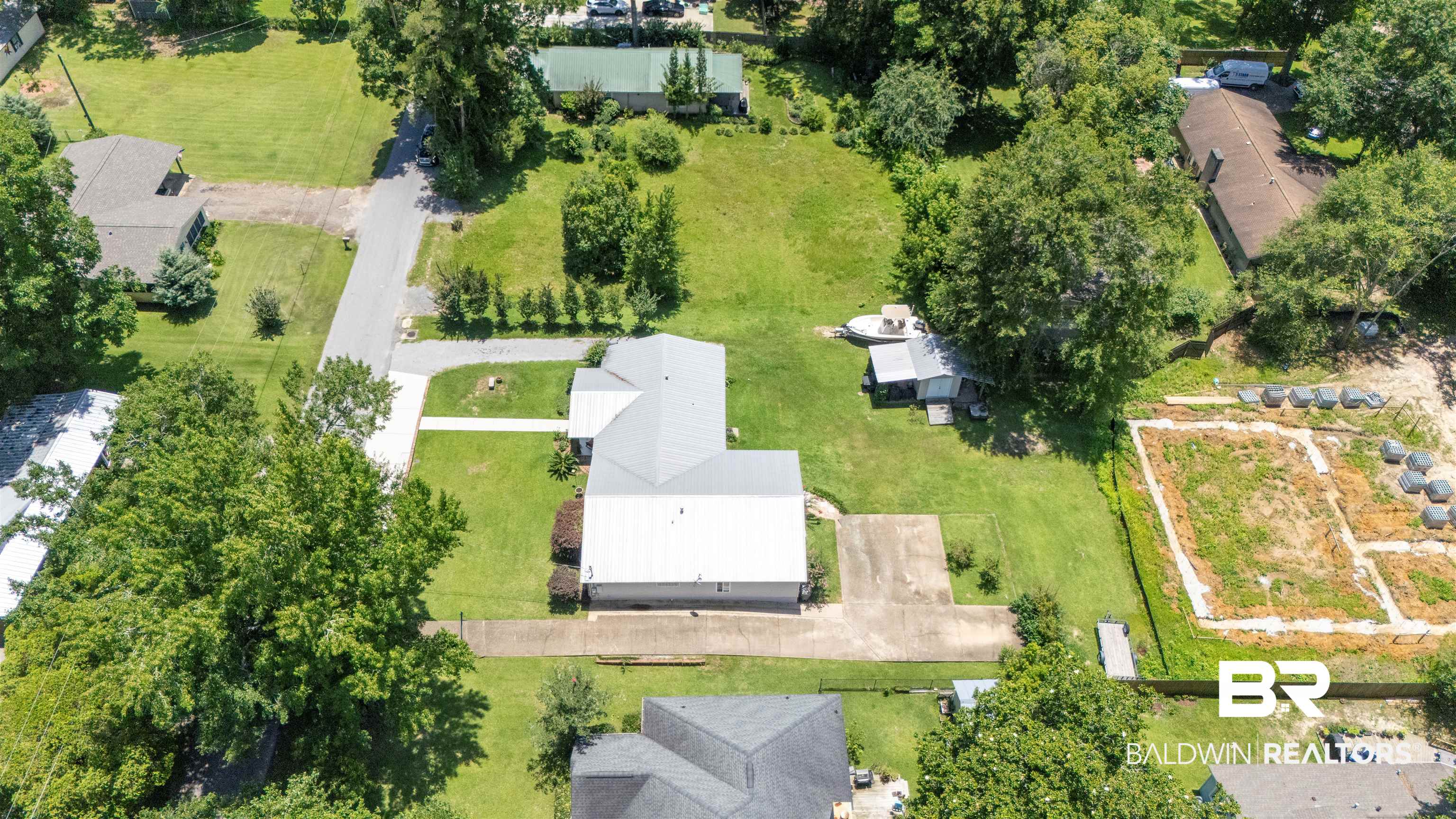 1615 5th Street Daphne, AL 36526 - Photo 27 of 28 Overhead property perspective featuring a residence with a light gray roof, an extended driveway, and surrounding green lawn