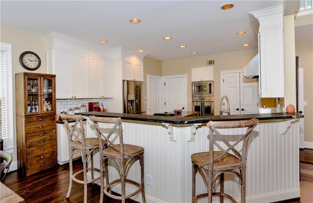 265 Windsor Gate Cove Northeast Atlanta, GA 30342 - Photo 20 of 62 a kitchen with stainless steel appliances kitchen island granite countertop a table chairs in it and wooden floors