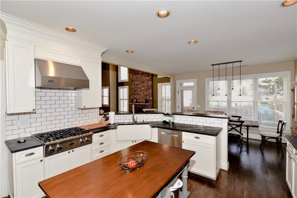 265 Windsor Gate Cove Northeast Atlanta, GA 30342 - Photo 23 of 62 a kitchen with stainless steel appliances granite countertop a stove a sink dishwasher and white countertops with wooden floor