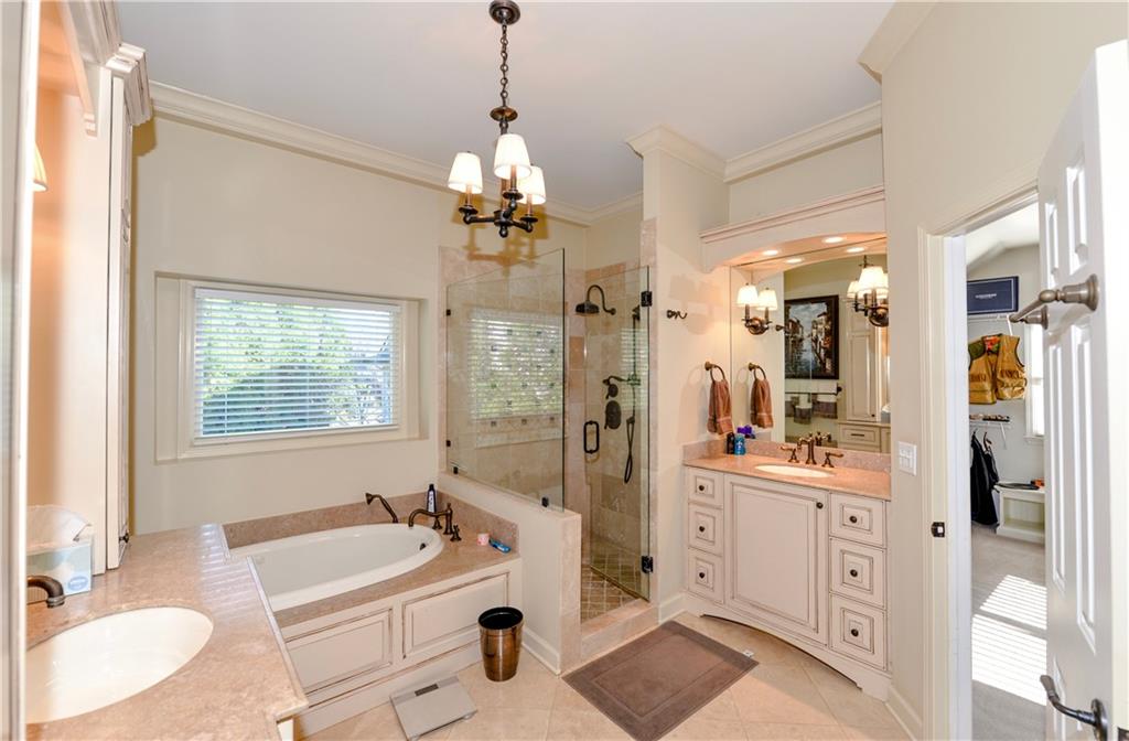 265 Windsor Gate Cove Northeast Atlanta, GA 30342 - Photo 34 of 62 a spacious bathroom with a double vanity sink a large mirror and a bathtub