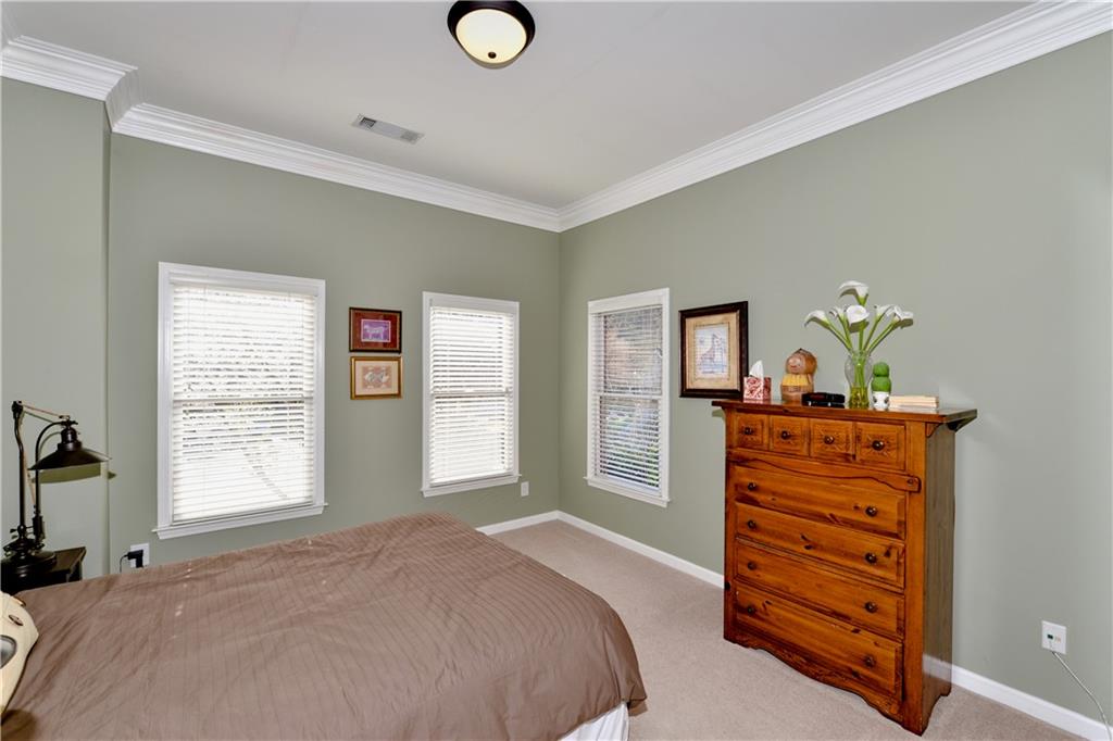 265 Windsor Gate Cove Northeast Atlanta, GA 30342 - Photo 45 of 62 a bedroom with a bed and dresser with mirror
