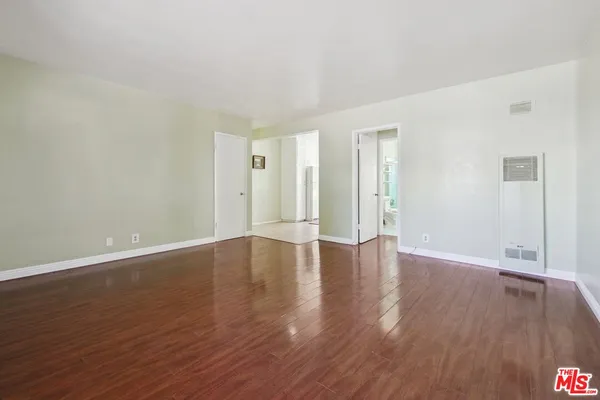 a view of an empty room with wooden floor and window