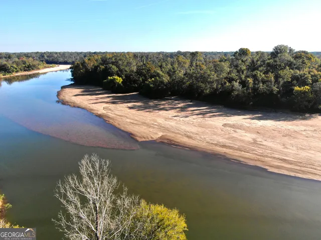a sign board with yard and trees in the background
