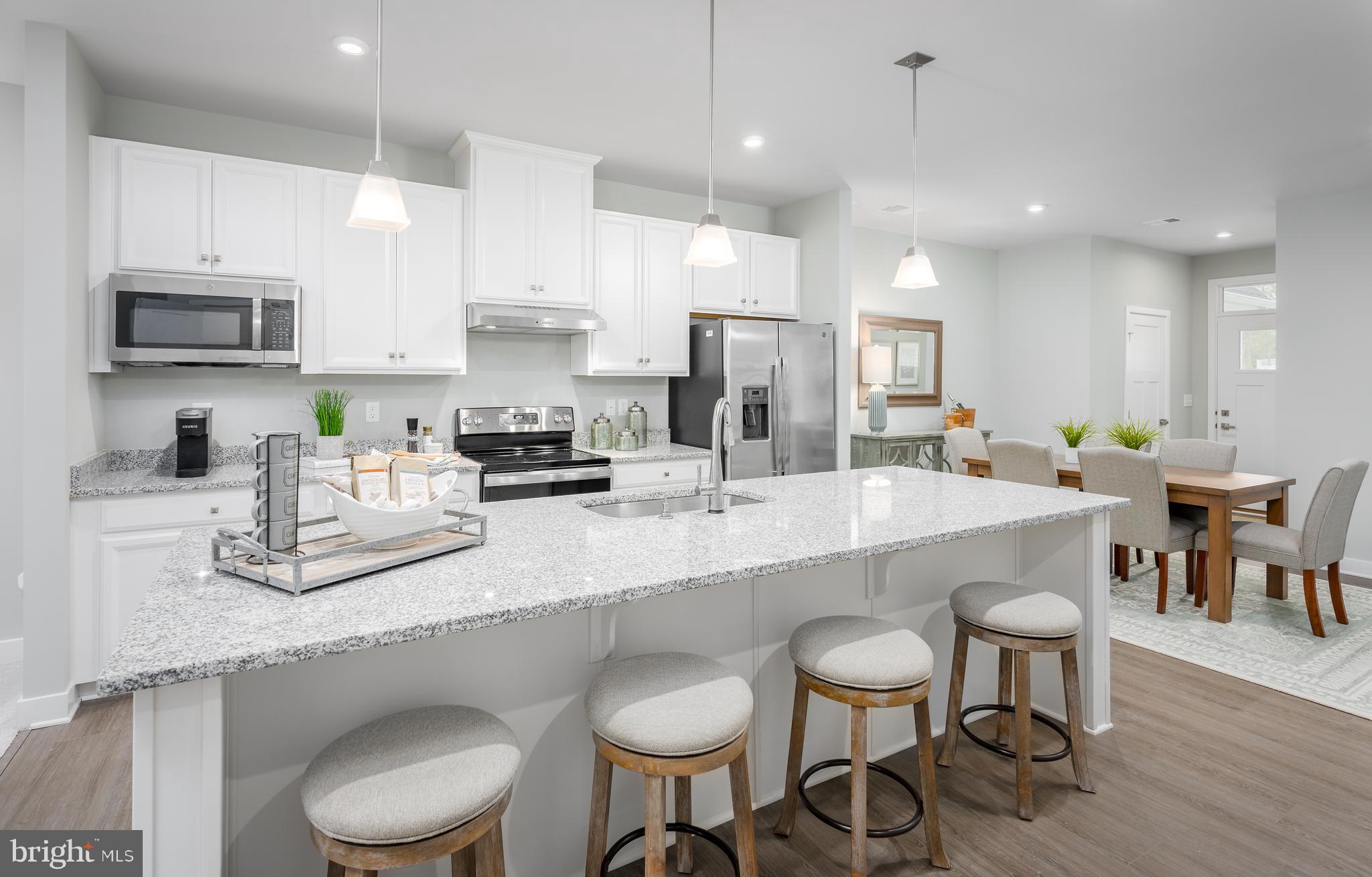 a kitchen with stainless steel appliances granite countertop a white table and chairs in it