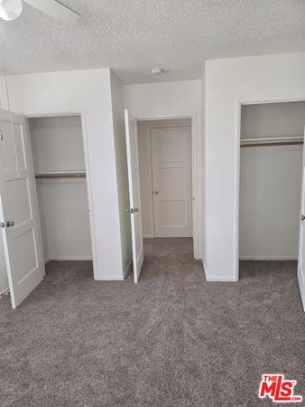 an empty room with a chandelier fan and windows