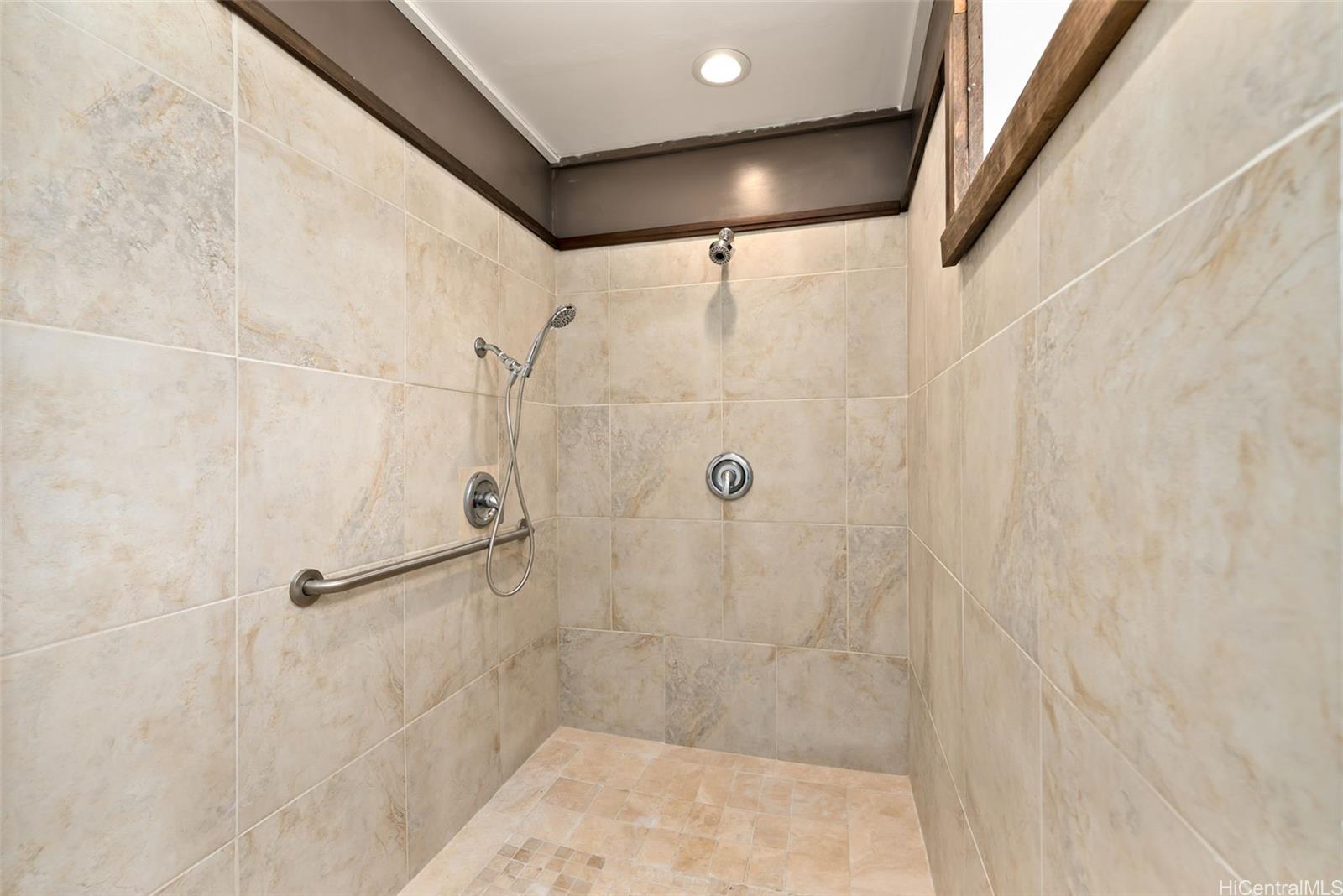2811 Henry Street Honolulu, HI 96817 - Photo 20 of 25 Wash your cares away in this beautifully upgraded walk-in shower, featuring elegant neutral tile, modern fixtures, and thoughtful accessibility.