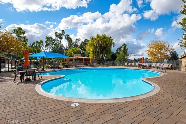 a view of a swimming pool with a table and chairs under an umbrella