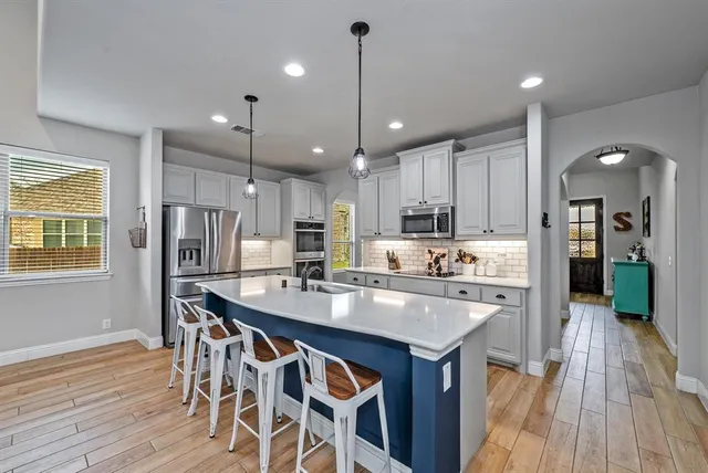 a kitchen with kitchen island stainless steel appliances a sink and wooden floor