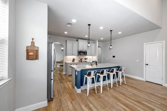 a kitchen with stainless steel appliances a dining table chairs stove refrigerator and wooden floor