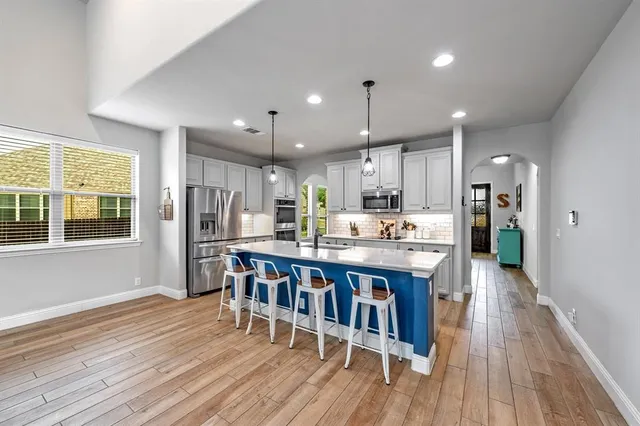 a kitchen with kitchen island white cabinets stainless steel appliances a sink and a window