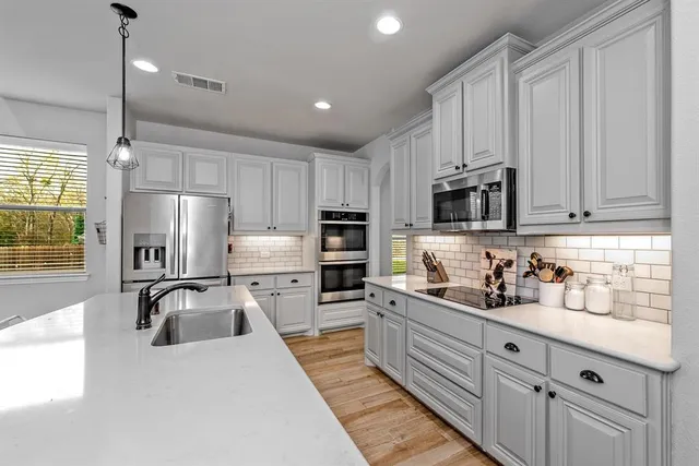 a kitchen with kitchen island granite countertop a stove a sink a dining table and chairs with wooden floor