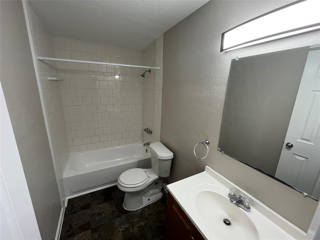 9558 Rylie Crest Drive Dallas, TX 75217 - Photo 8 of 14 Bathroom featuring a white subway tile tub surround, dark wood-finish flooring, a contemporary vanity with an integrated sink, a large wall-mounted mirror, and a modern rectangular light fixture