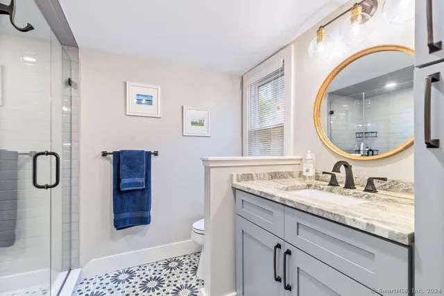 a bathroom with a granite countertop shower a sink and a mirror