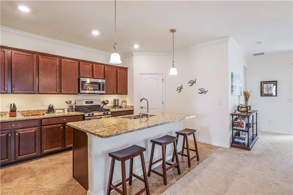 a kitchen with kitchen island granite countertop a table chairs sink and cabinets