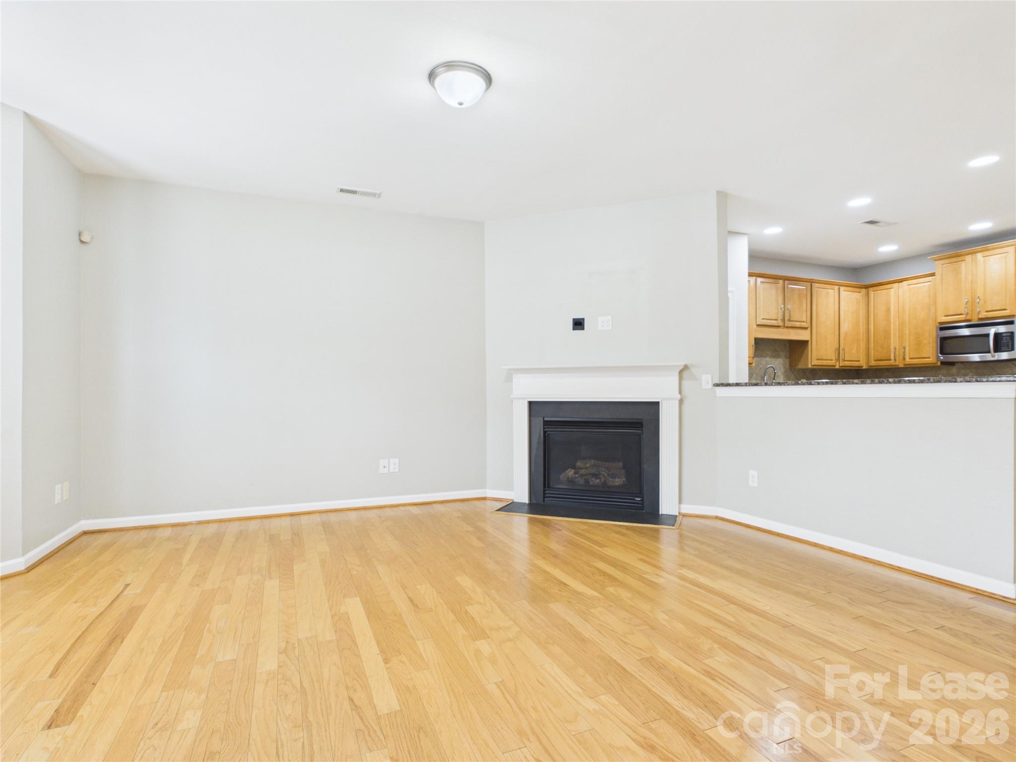 5690 Stafford Road Charlotte, NC 28215 - Photo 6 of 25 a view of empty room with wooden floor and fireplace