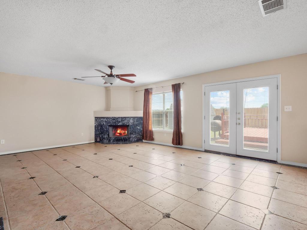 2727 High Point Drive Round Rock, TX 78664 - Photo 20 of 31 Unfurnished living room featuring a textured ceiling, french doors, ceiling fan, a fireplace, and baseboards