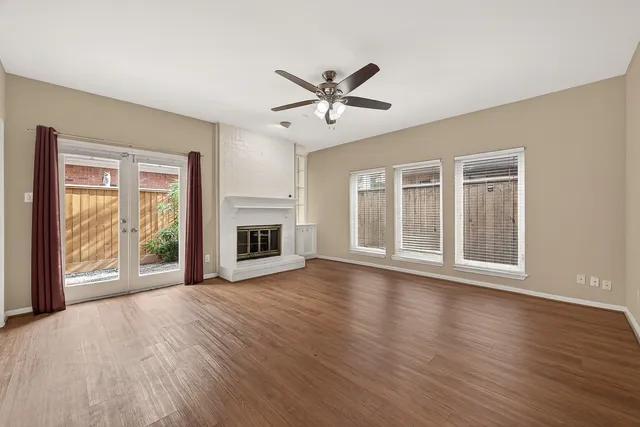 a view of an empty room with a window and wooden floor