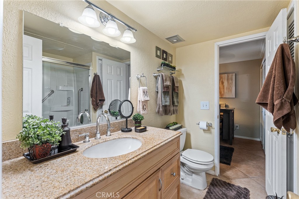 10655 Lemon Avenue Rancho Cucamonga, CA 91737 - Photo 18 of 32 a bathroom with a granite countertop sink a toilet and a mirror