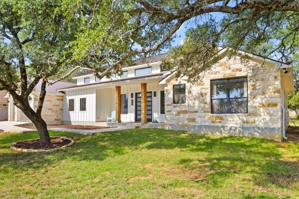 a view of a house with a yard and large tree