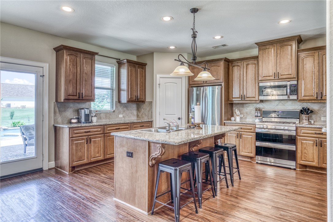 586 Ruby Drive Bellville, TX 77418 - Photo 12 of 50 a kitchen with stainless steel appliances granite countertop wooden floor a sink a stove and a refrigerator
