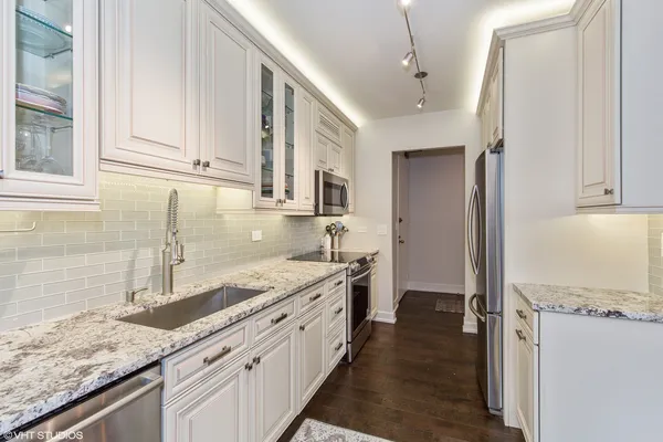 a kitchen with stainless steel appliances granite countertop a sink and a white cabinets