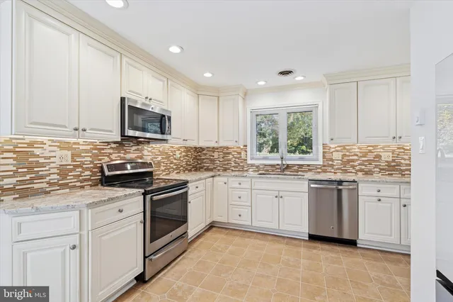 a kitchen with granite countertop white cabinets white stainless steel appliances with a sink and dishwasher