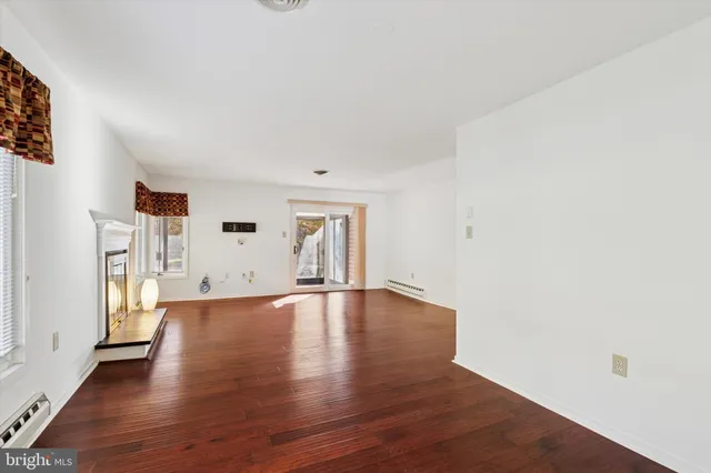 a view of an empty room with window and wooden floor