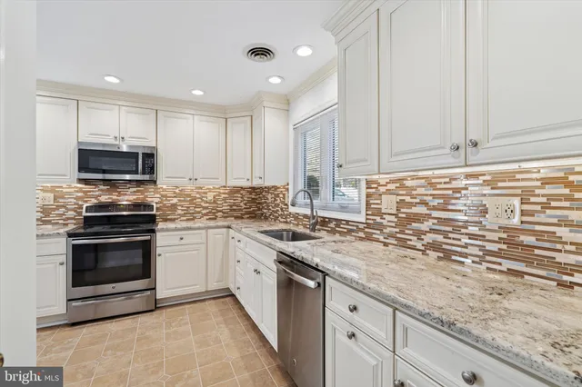 a kitchen with stainless steel appliances granite countertop a stove sink and cabinets