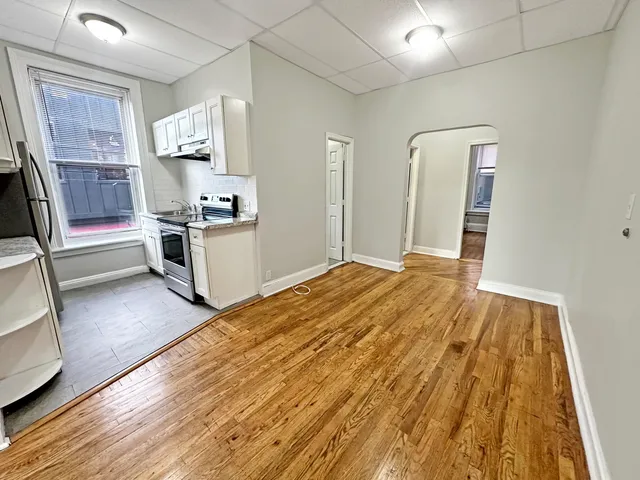 a open kitchen with white cabinets and wooden floor