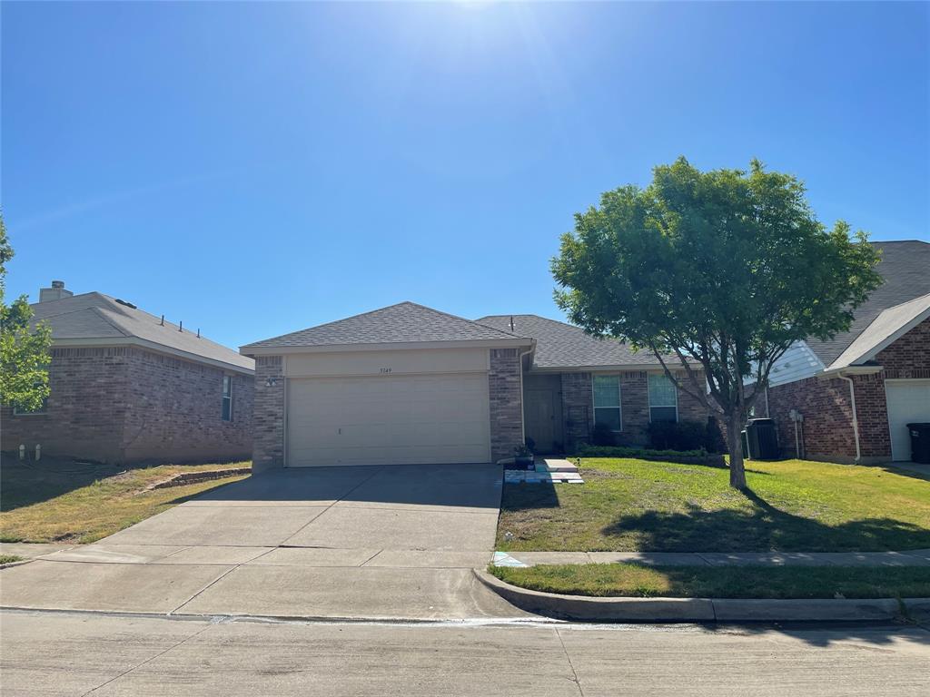 Ranch-style home featuring a front yard, concrete driveway, roof with shingles, and an attached garage