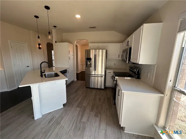 a kitchen with a refrigerator and white cabinets