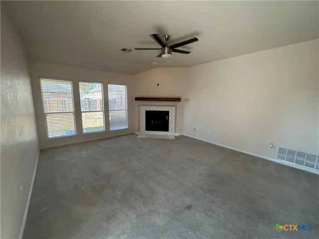 an empty room with a fireplace and windows