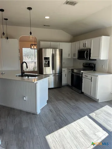 a kitchen with stainless steel appliances granite countertop a stove a sink dishwasher and a refrigerator with wooden floor