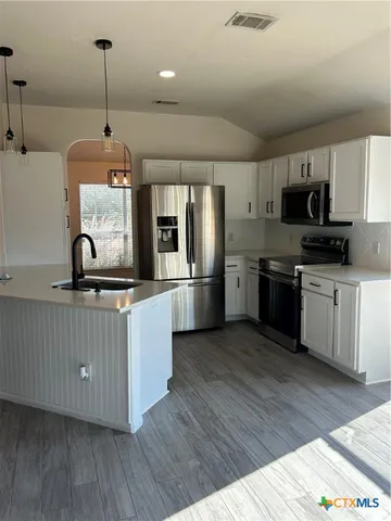 a kitchen with stainless steel appliances kitchen island granite countertop a stove a sink and a refrigerator