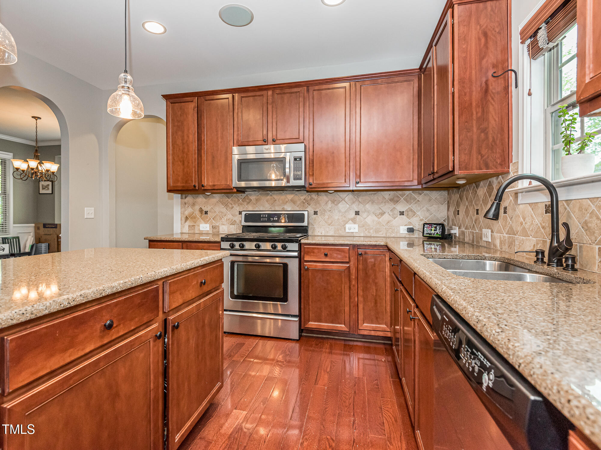 111 Gathering Place Durham, NC 27713 - Photo 13 of 44 a kitchen with stainless steel appliances granite countertop a stove a sink dishwasher and a microwave oven with wooden floor