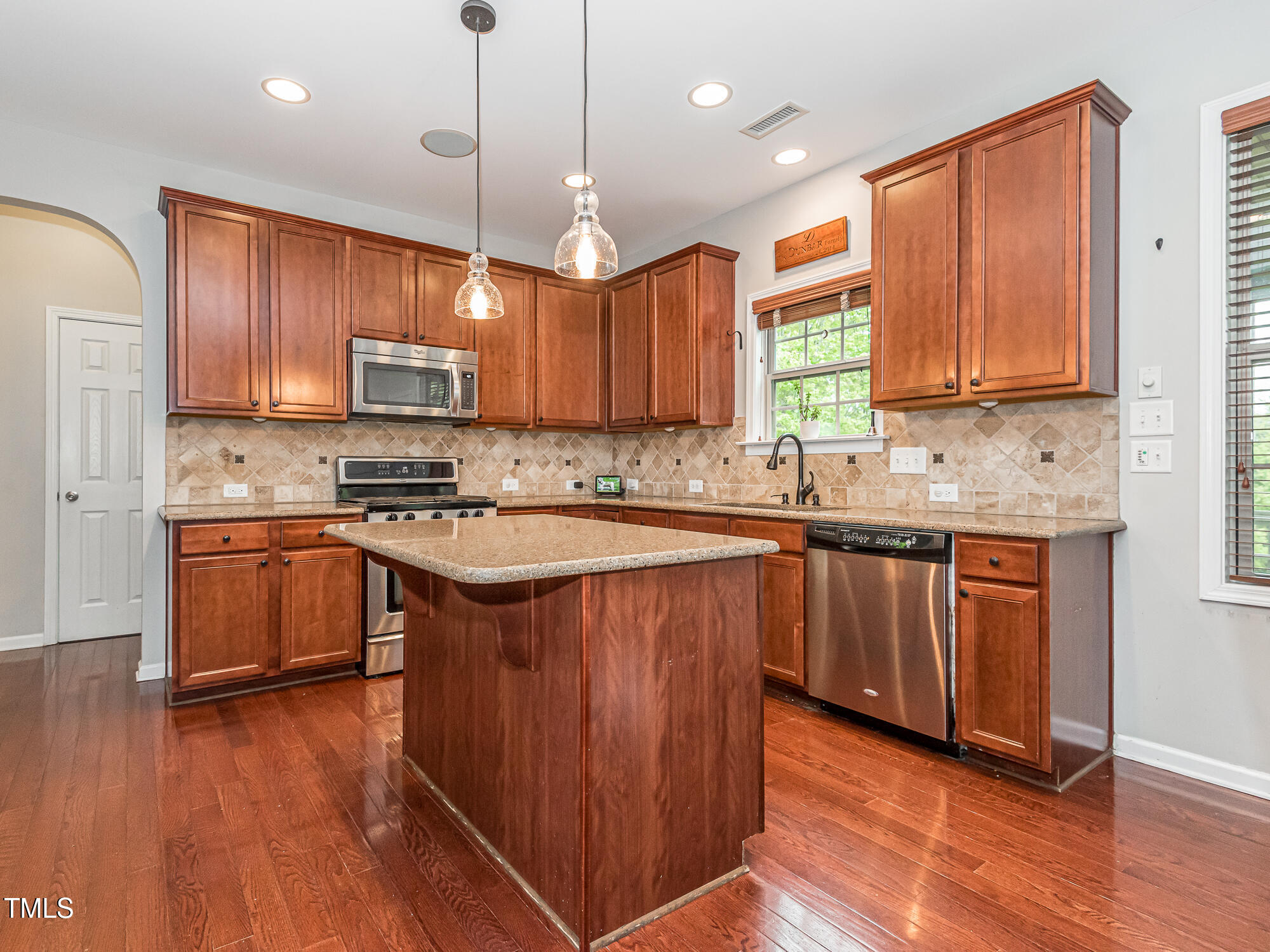111 Gathering Place Durham, NC 27713 - Photo 14 of 44 a kitchen with kitchen island granite countertop wooden floors stainless steel appliances a sink and a window