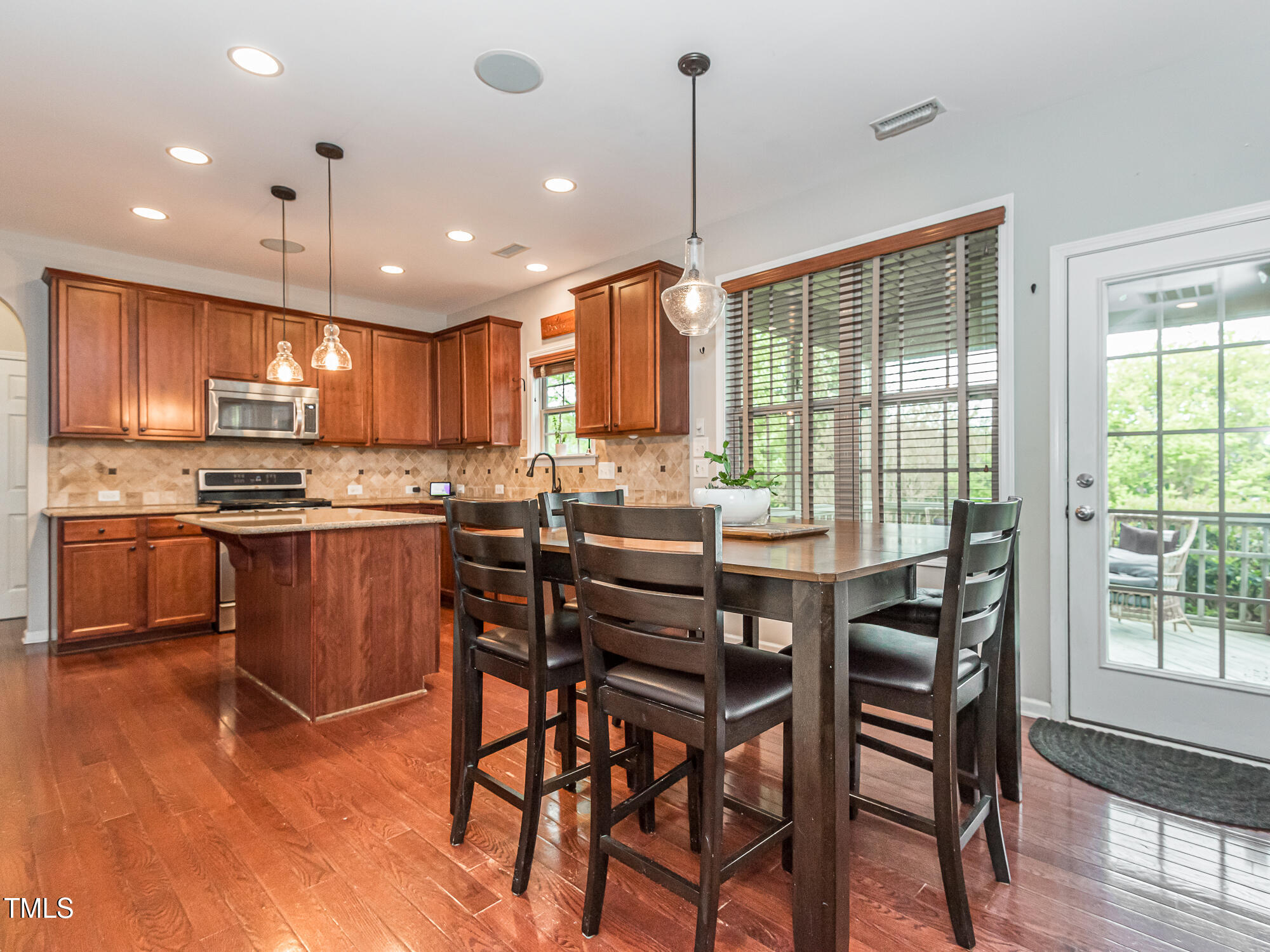 111 Gathering Place Durham, NC 27713 - Photo 17 of 44 a kitchen with stainless steel appliances kitchen island granite countertop a stove a sink a dining table and chairs with wooden floor
