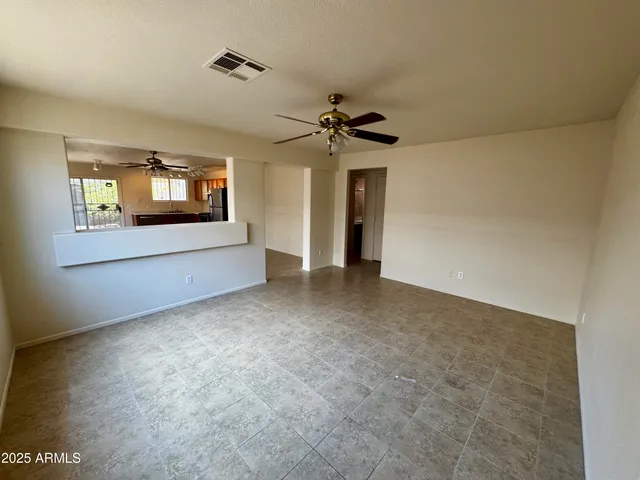 a view of an empty room with a window and a kitchen