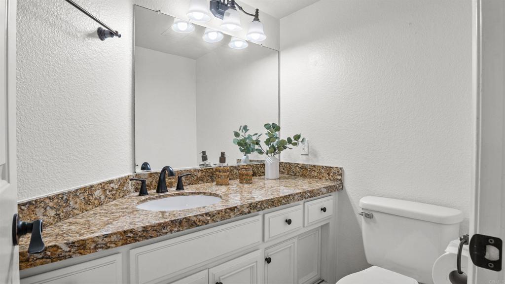 354 Lustrosos Street Oceanside, CA 92057 - Photo 17 of 75 a bathroom with a granite countertop sink a toilet and mirror