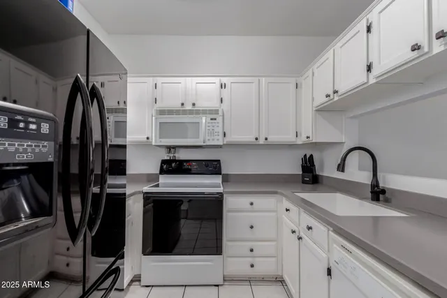 a kitchen with white cabinets and appliances