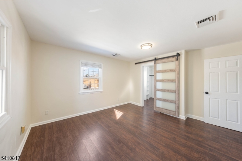 an empty room with wooden floor closet and windows