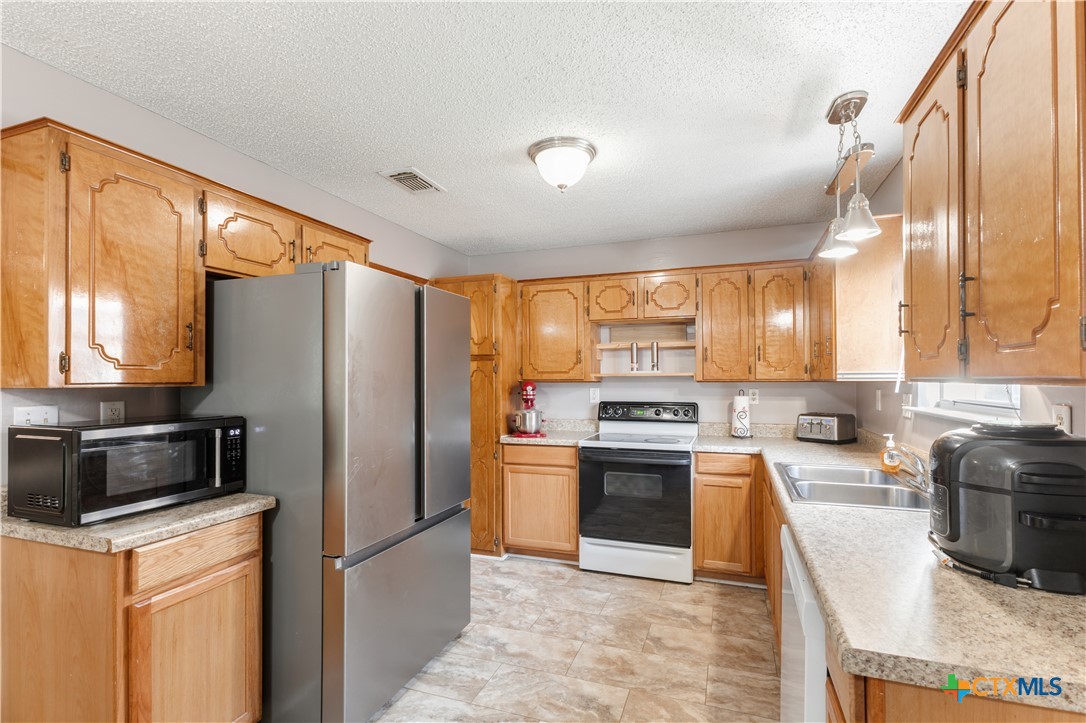 144 Jordan Loop Nolanville, TX 76559 - Photo 7 of 20 a kitchen with stainless steel appliances granite countertop a refrigerator a stove a sink a oven with a dining table and chairs